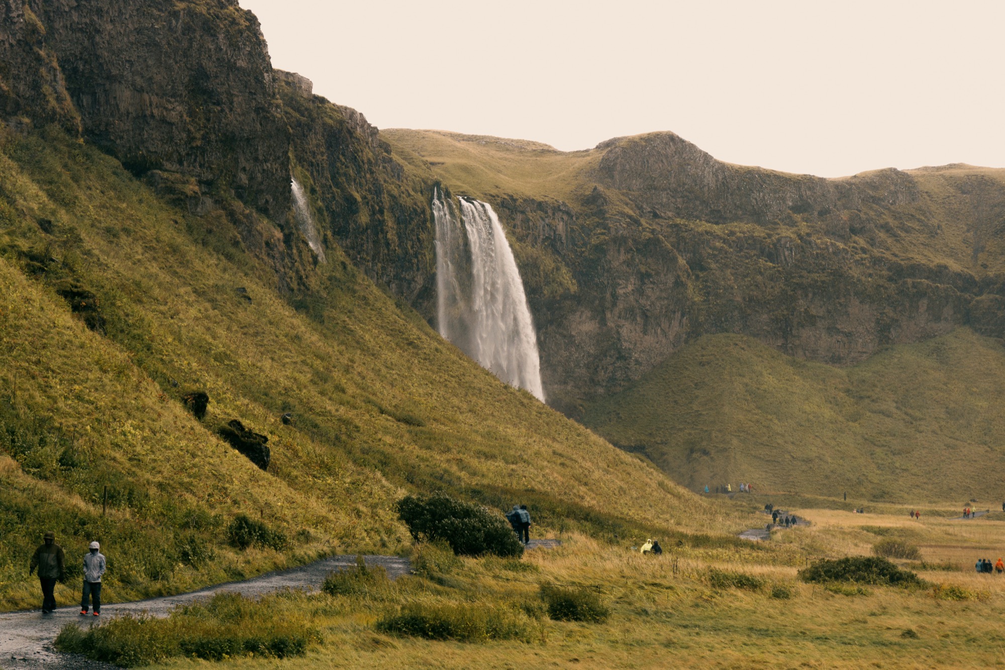 Una cascada descendiendo por una ladera verde al atardecer