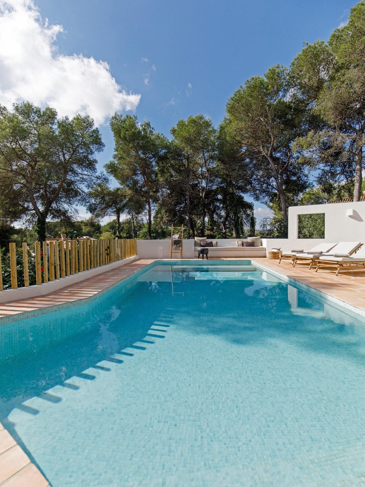 A serene poolside surrounded by pine trees at a VIVLA home