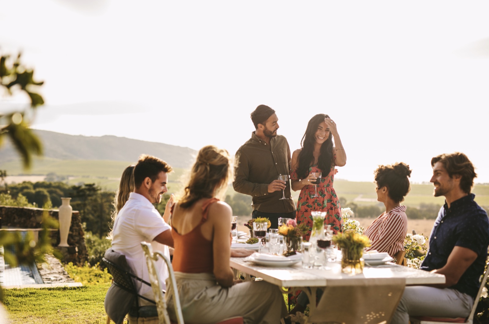 Amigos compartiendo una larga cena al atardecer en una casa VIVLA